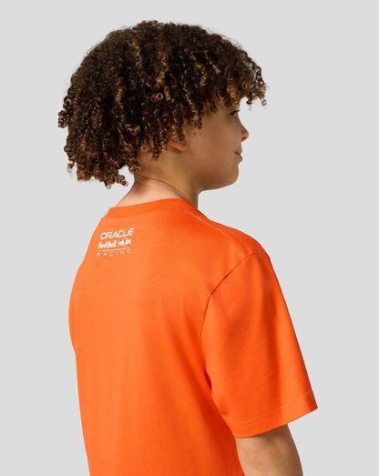 Side view of a child in an orange Max Verstappen puzzle T shirt showing a large white graphic on the chest and Castore patch on the sleeve
