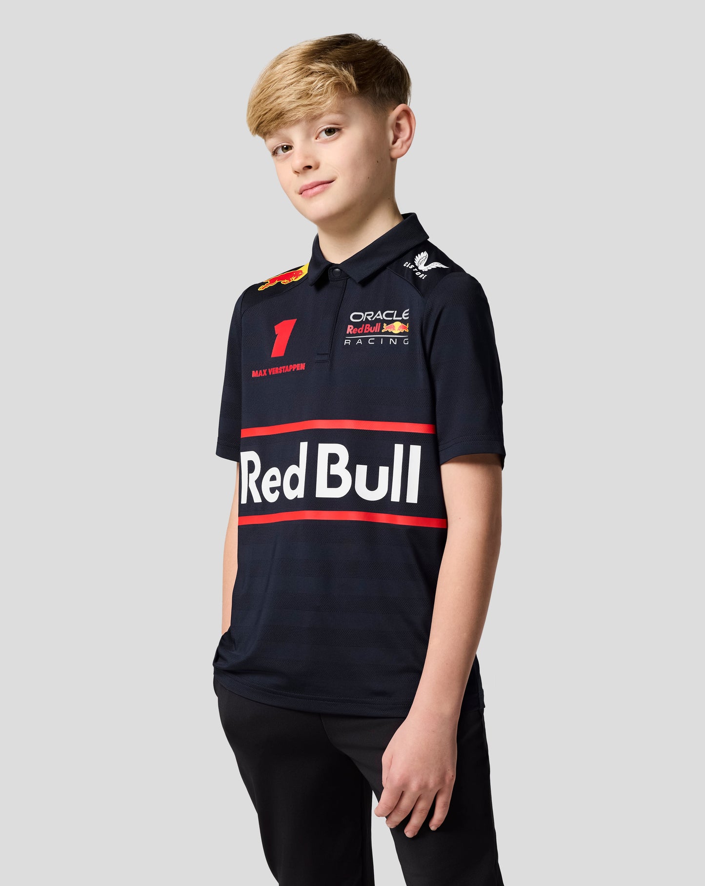 Young boy wearing a navy Oracle Red Bull Racing Junior polo with Verstappen artwork and team logos