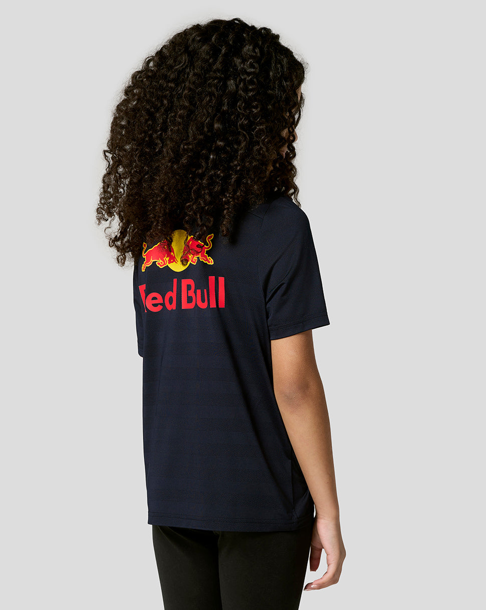 Back view of a child wearing a night sky navy Red Bull Racing junior polo with a large Red Bull graphic on the back