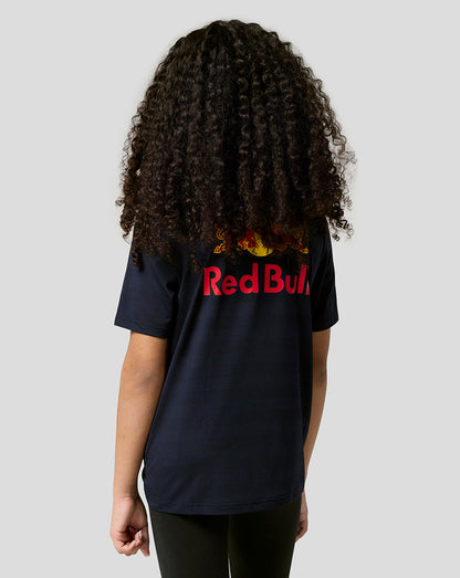 Back view of a child with curly hair wearing a navy Red Bull Racing T shirt with a large Red Bull logo on the back