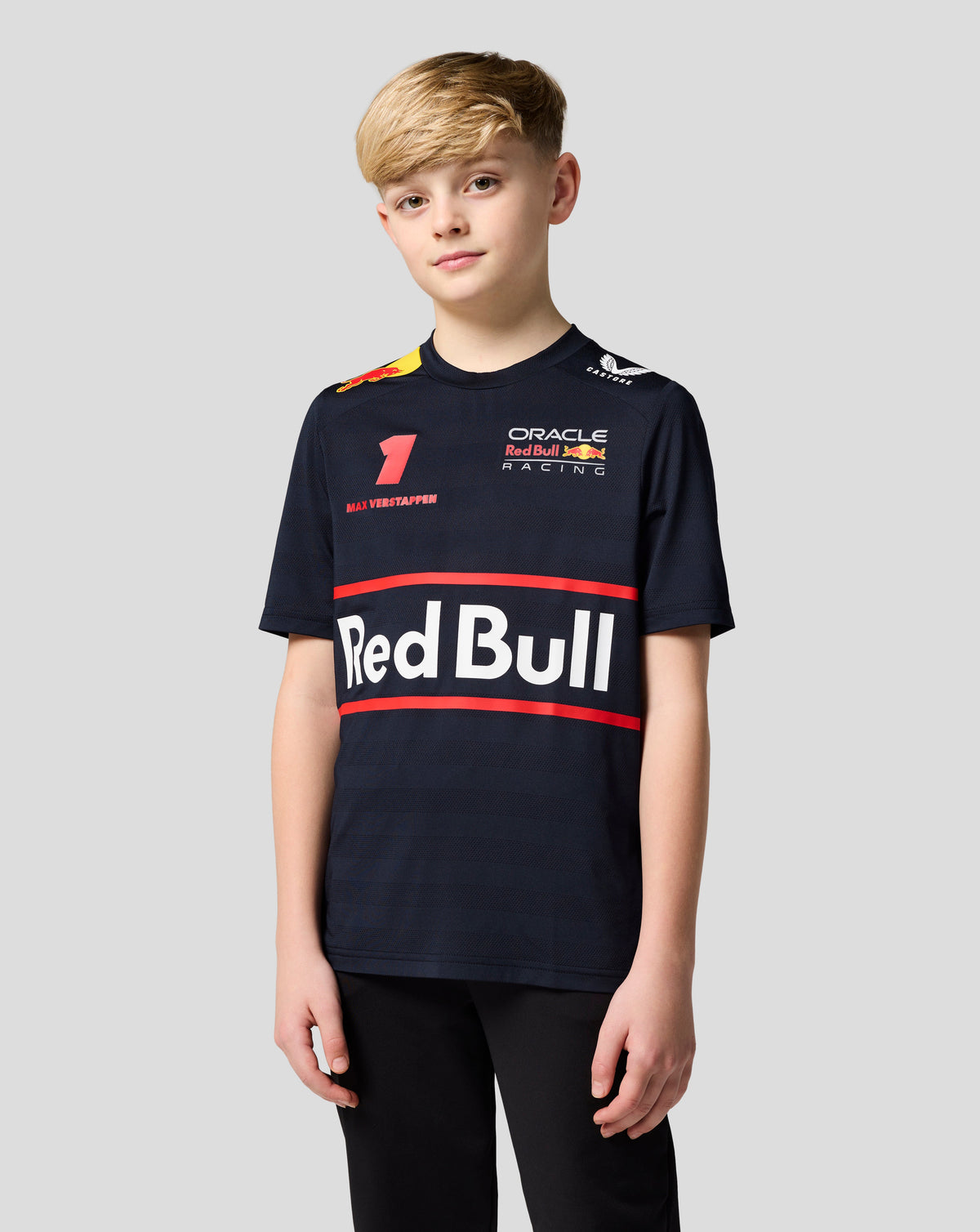 Smiling child in navy night sky Oracle Red Bull Racing Junior Teamline shirt with Verstappen artwork and number.
