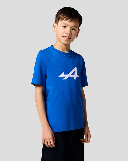 Boy in blue Alpine Core Essentials T-shirt with bold white logo on the front, standing casually.