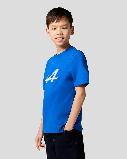 Young boy in lapis blue Alpine Juniors Core Essentials T shirt with a bold white logo on the chest.