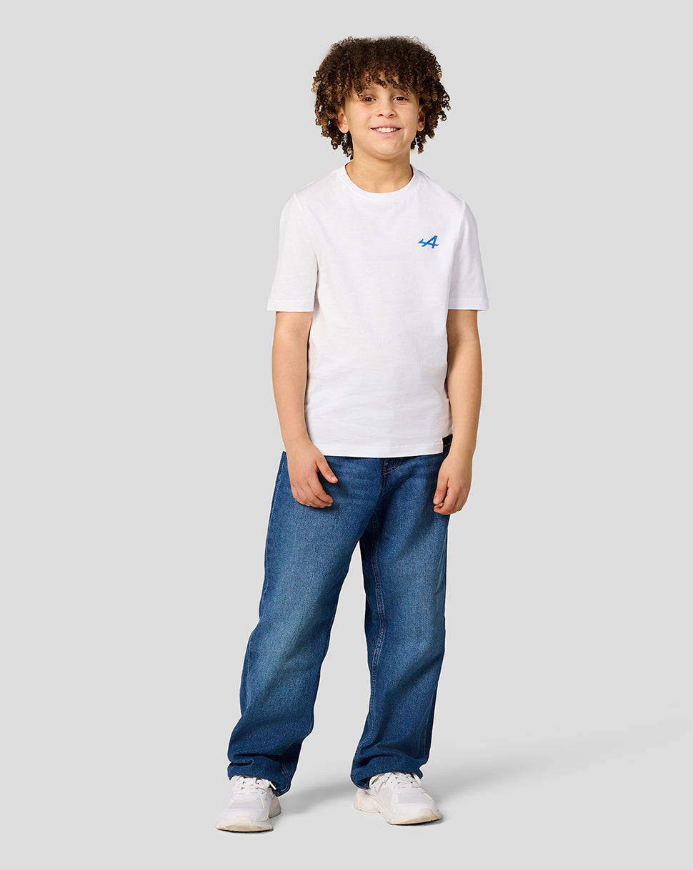 Front view of a white Alpine Juniors graphic T shirt with blue left chest logo worn by a smiling kid
