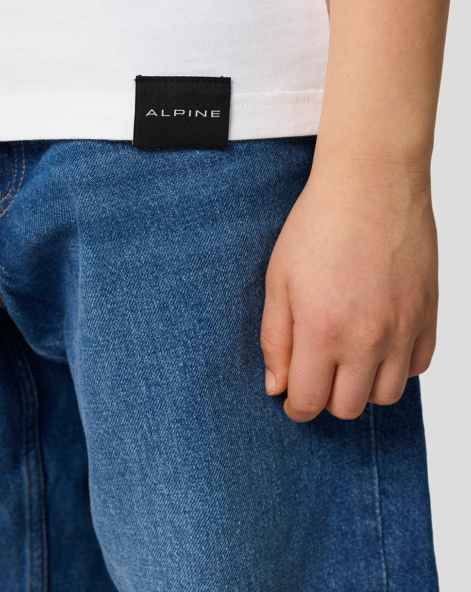 Close-up of the back hem on a white Alpine Juniors Graphic T-Shirt with a black ALPINE tag.