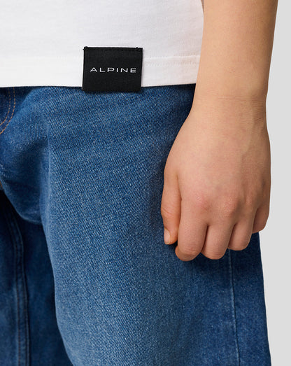 Close-up of the back hem on a white Alpine Juniors Graphic T-Shirt with a black ALPINE tag.
