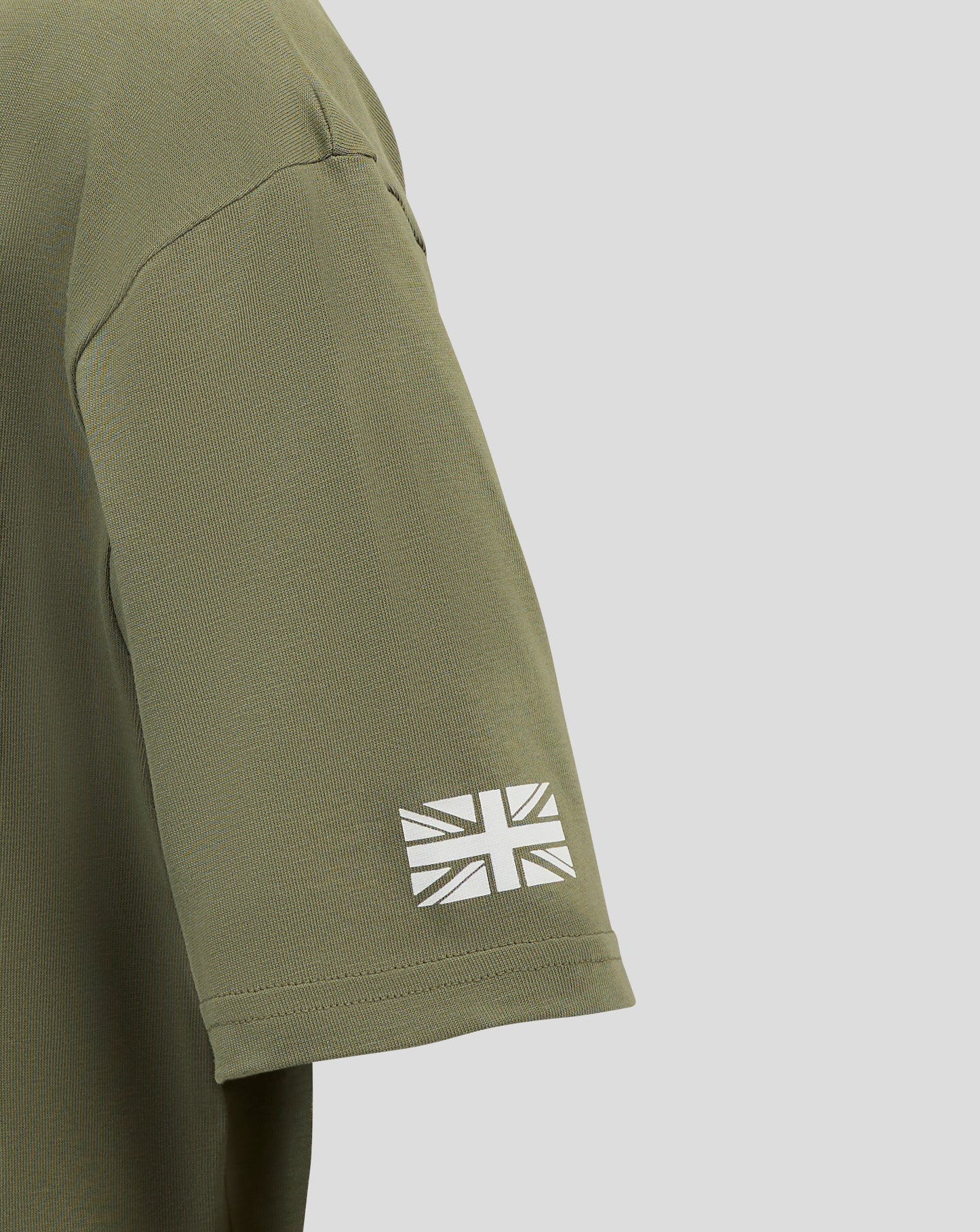 Close up of olive green Alpine junior T shirt sleeve with a white Union Jack graphic near the cuff