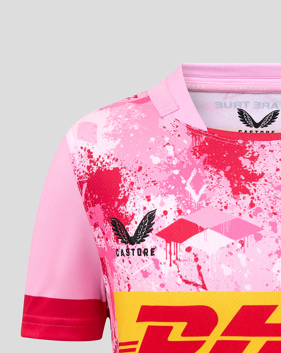 Close-up of pink Harlequins junior away replica shirt with splatter print and Castore logo on chest