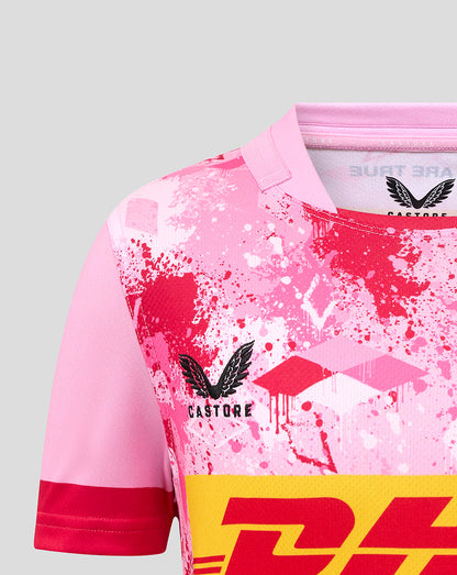 Close-up of pink Harlequins junior away replica shirt with splatter print and Castore logo on chest