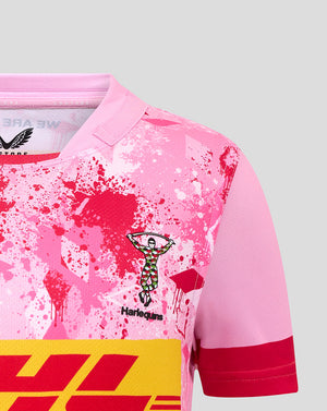 Close up of pink Harlequins junior away shirt showing the club crest and splatter print.