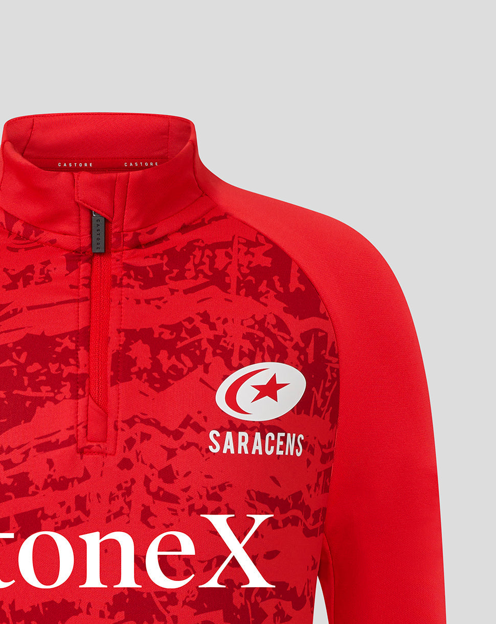 Close-up of red Saracens junior midlayer top with a zip collar and white Saracens logo over an abstract print