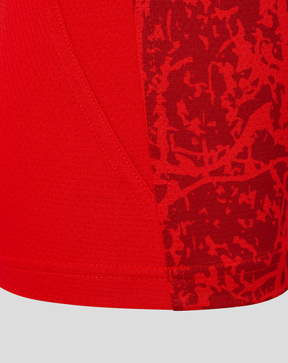 Close up of red textured fabric and abstract camo pattern on the lower front of the Saracens junior matchday tee near the side seam