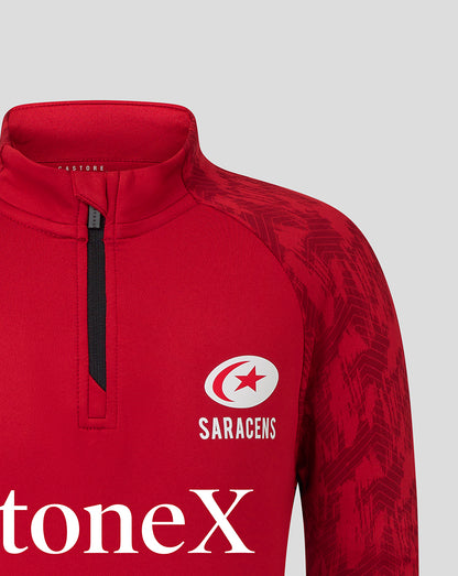 Close-up of red Saracens training top showing crest on the chest and bold StonEx branding across the front.