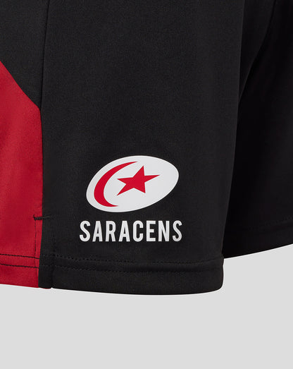 Close-up of Saracens logo on the lower left side of black shorts with a red panel