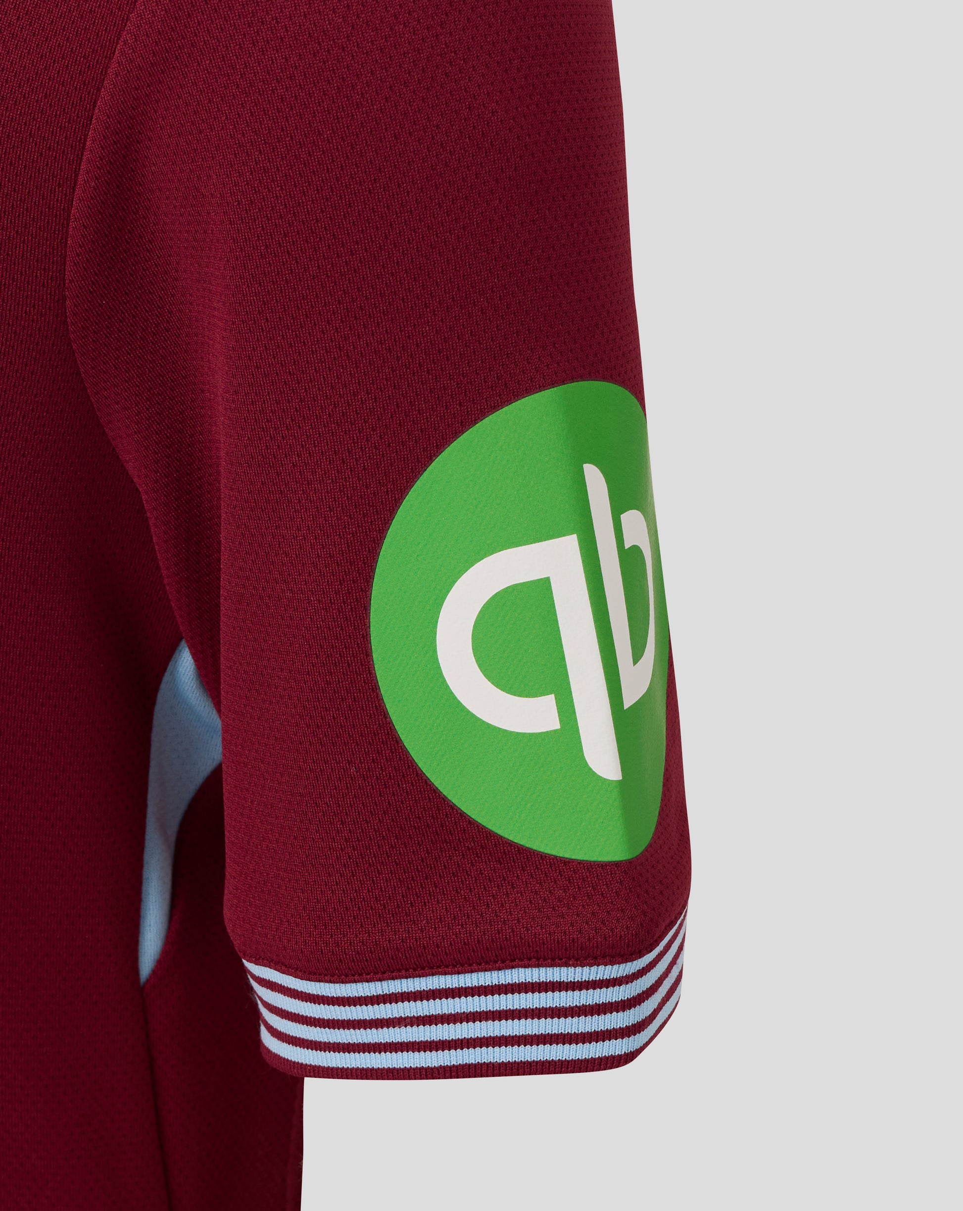 Close-up of burgundy sleeve with a bright green sponsor patch on the West Ham junior home shirt