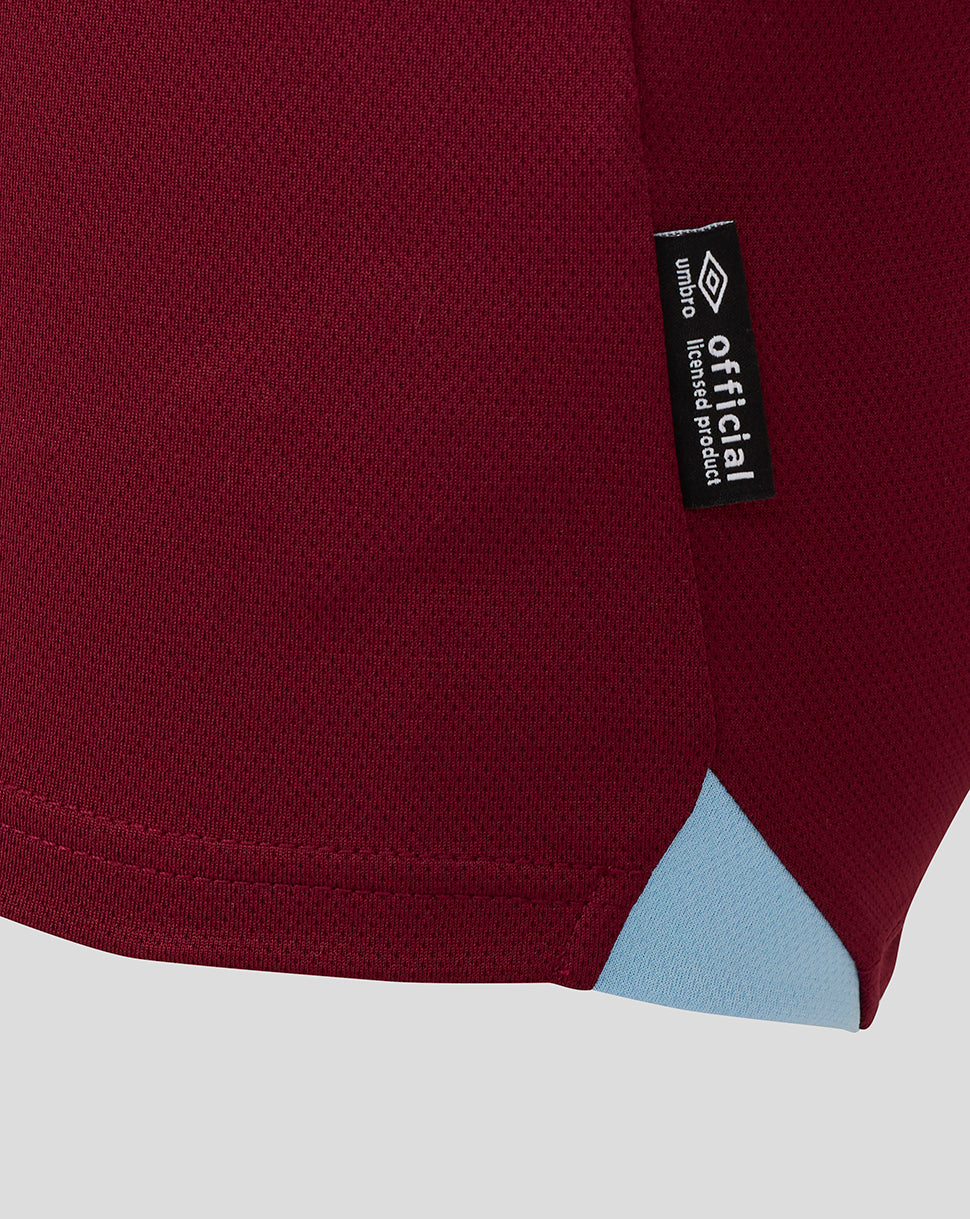 Close-up of West Ham junior home shirt fabric with an official licensed product tag on maroon material