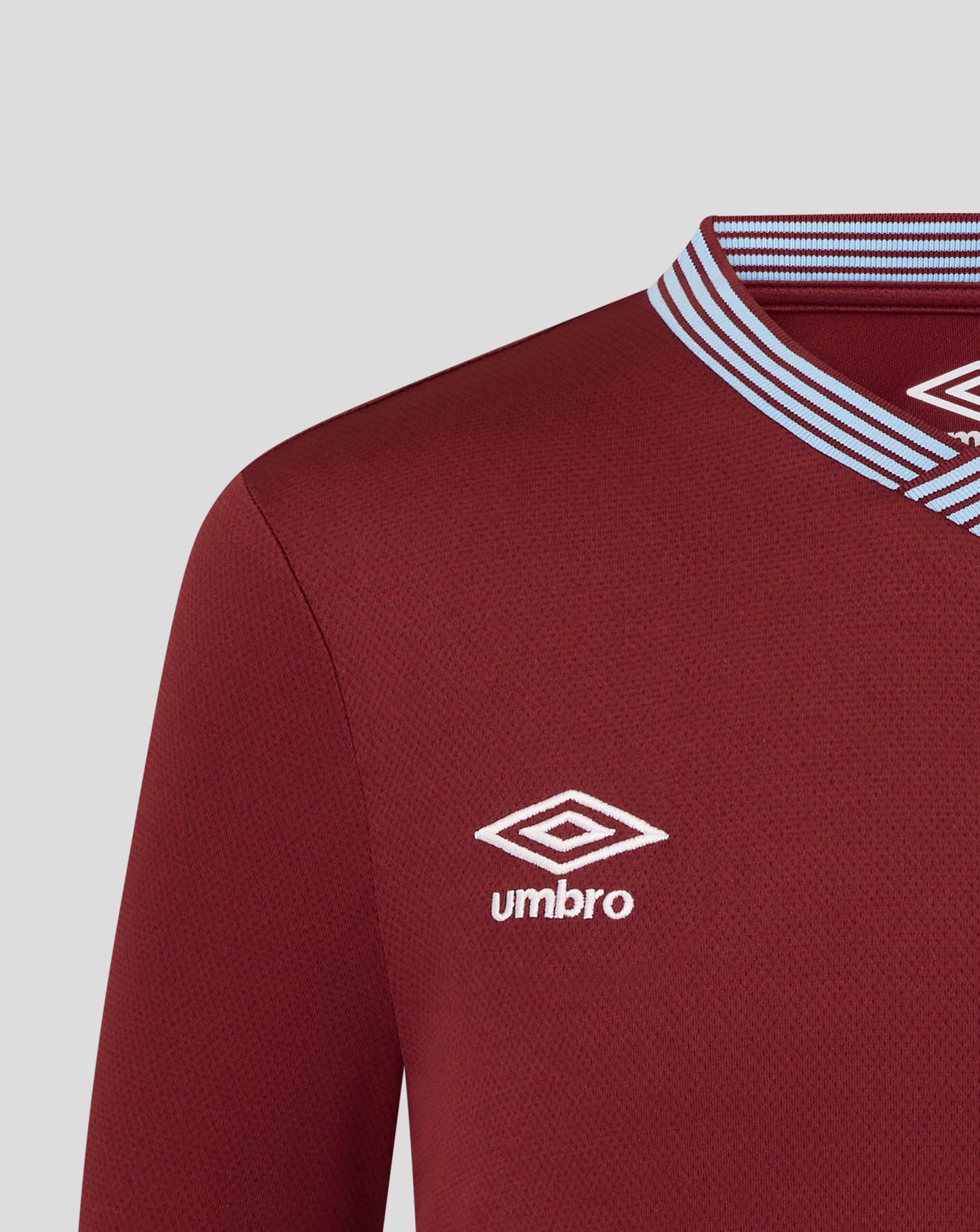 Lower front chest of maroon West Ham Junior shirt showing the Umbro logo