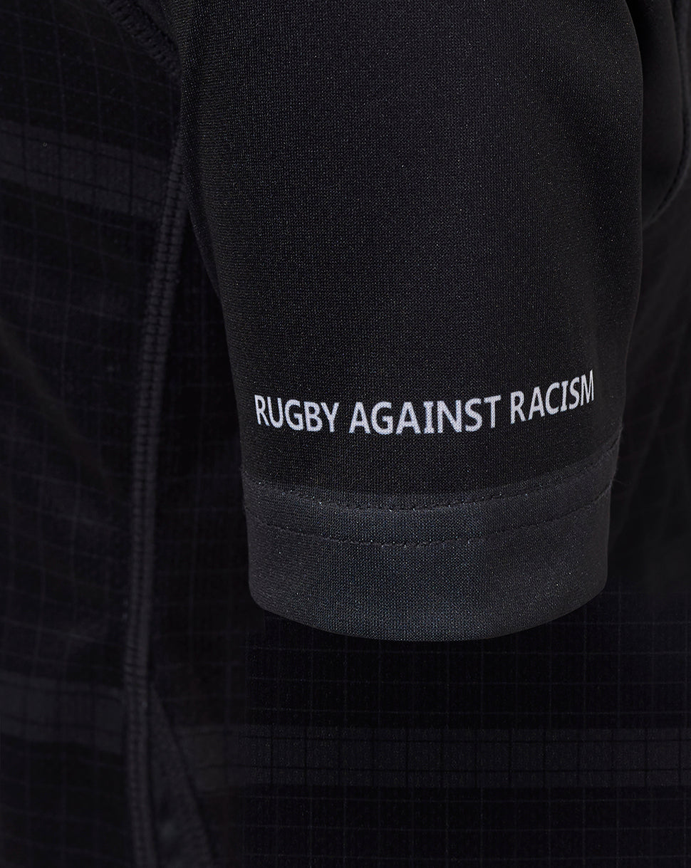 Close up of black Bath Rugby junior replica shirt sleeve with Rugby Against Racism slogan in white.