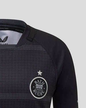 Close up of Bath Rugby Junior replica shirt chest with crest, star, and subtle grid pattern on dark fabric