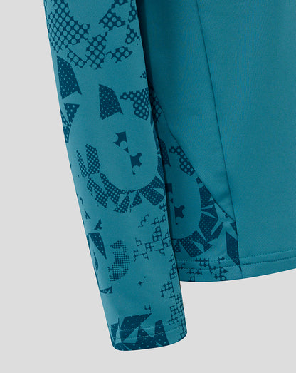 Sleeve close-up showing abstract geometric print on storm blue junior England performance midlayer.