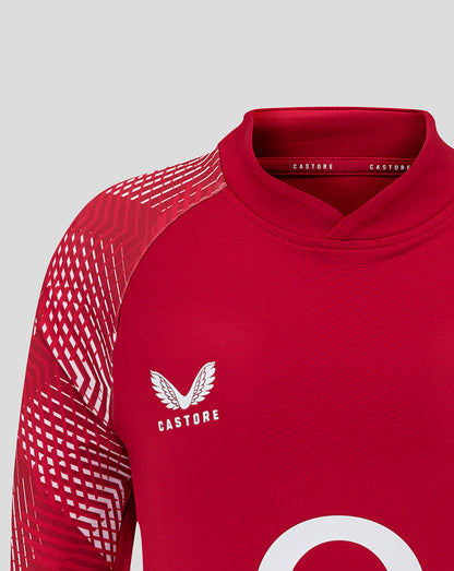 Close up of a red England Rugby junior pre match drill top showing the rose crest on the chest and Castore branding.