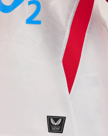 Front close up of junior England rugby home shirt showing white fabric with a red angled side panel and Castore badge at hem.