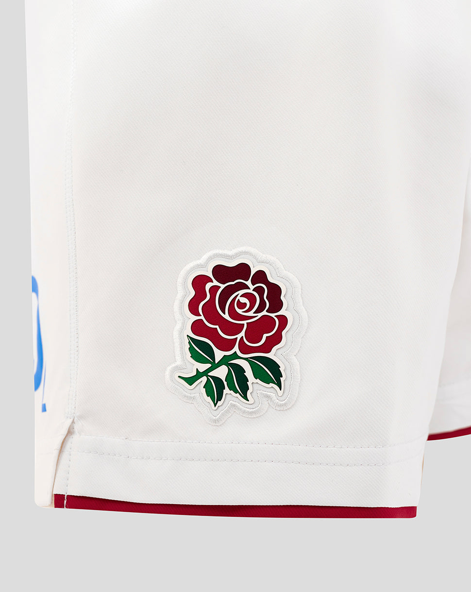 Close up of white shorts fabric showing the embroidered Rose crest patch on the left thigh