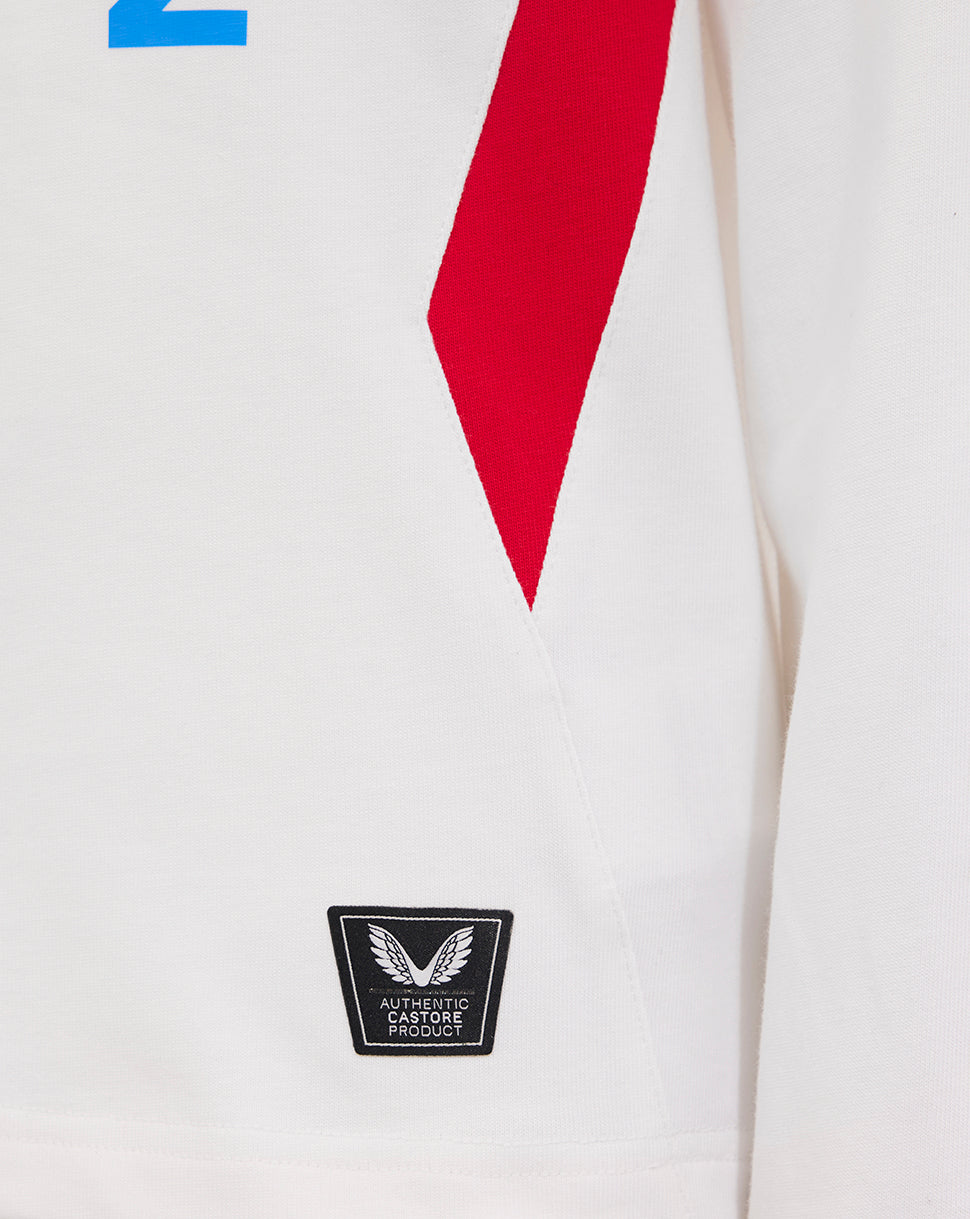 Close-up of white junior rugby shirt showing a red side panel and authentic Castore product badge near the hem