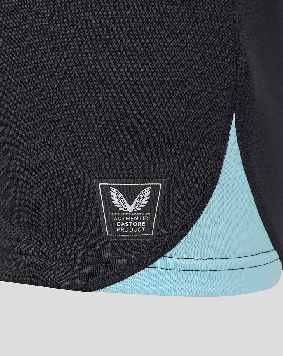 Close up of the lower front of the shirt showing the authentic Castore product badge on black fabric with turquoise trim