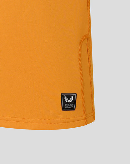 Close-up of orange shorts with a brand logo on a light gray background