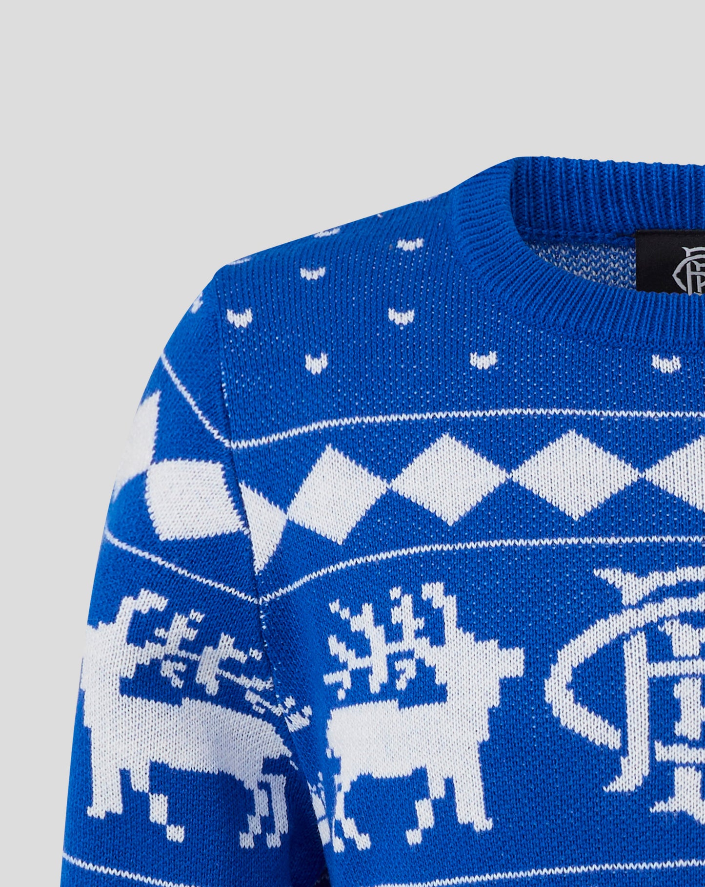 Close up of blue knit fabric showing a white snowflake motif and geometric patterns.