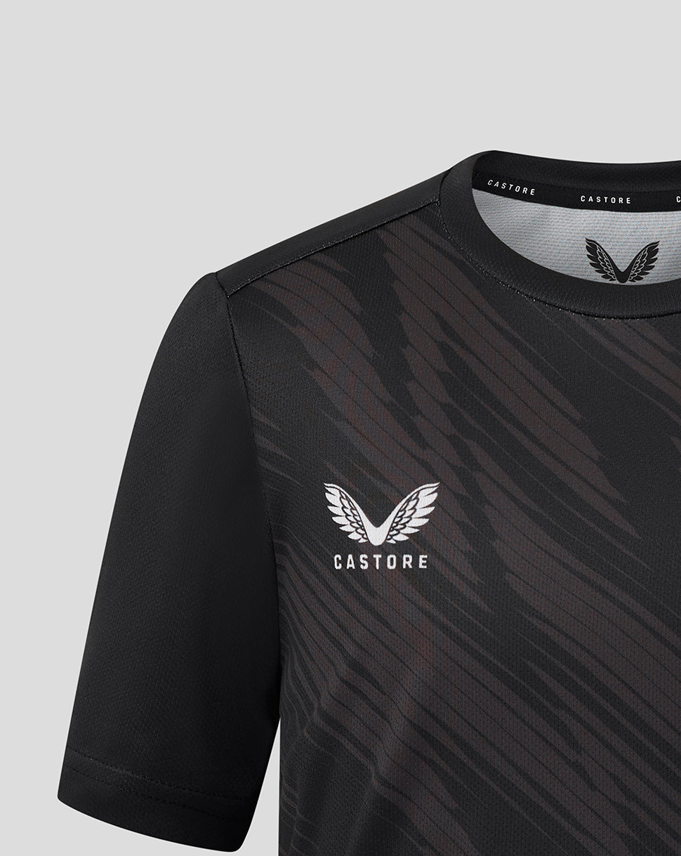 Front close up of black Leicester Tigers junior warm up shirt with white winged crest and Castore branding near the collar.