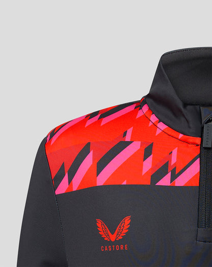 Close-up of Welsh Fire junior performance quarter-zip top showing bold red and pink geometric shoulder panels on dark fabric with Castore branding.