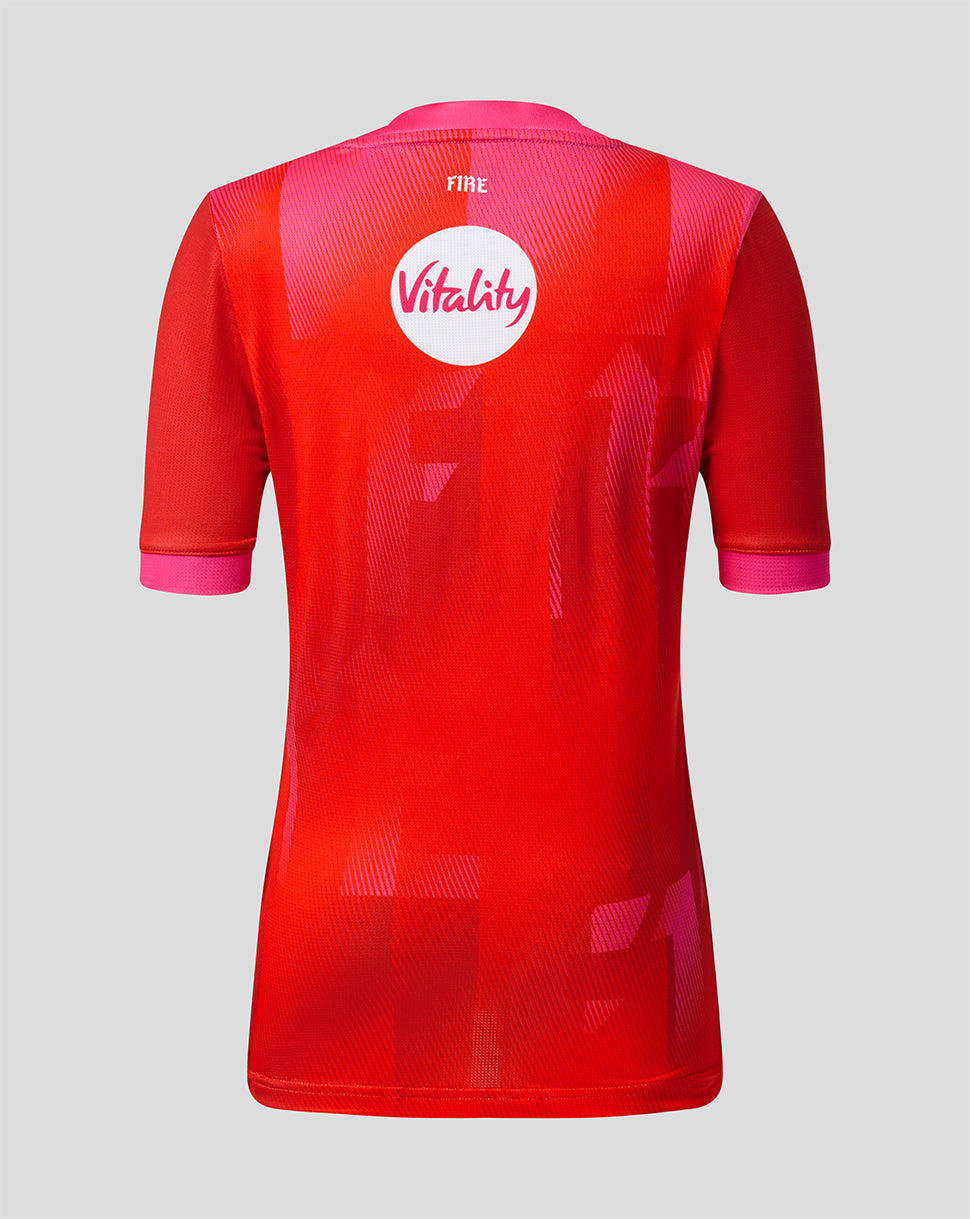 Back view of Welsh Fire 2026 junior short sleeve stretch jersey showing vibrant red geometric pattern and Vitality sponsor badge