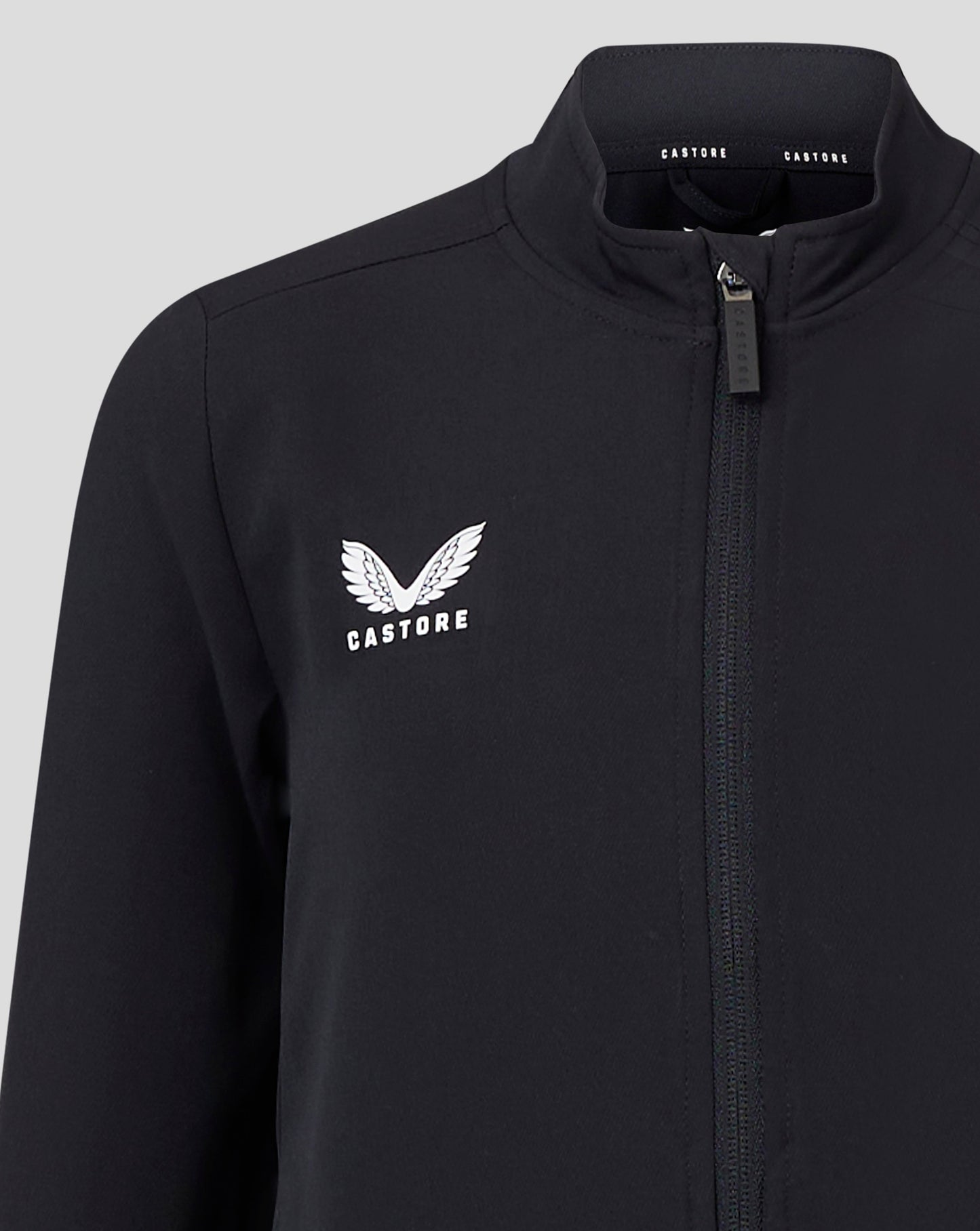 Close-up of black Junior Track Jacket showing funnel neck and front zipper with Castore branding on the collar.