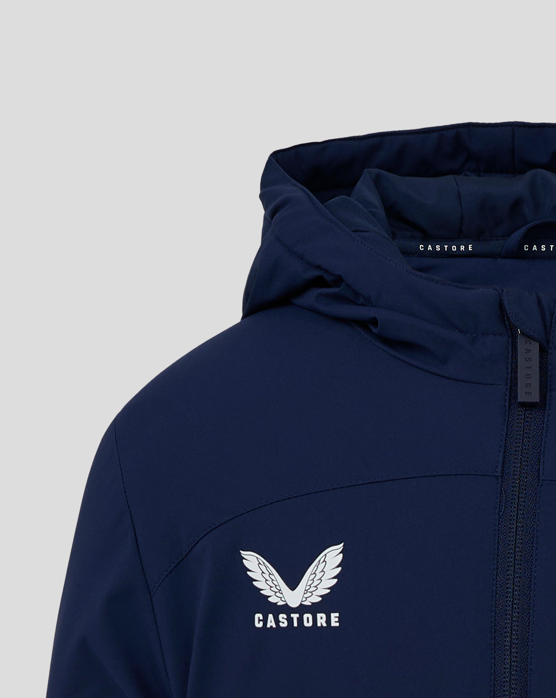 Close up of hood opening on navy Junior Bench Jacket, highlighting interior padding and Castore branding along the edge.