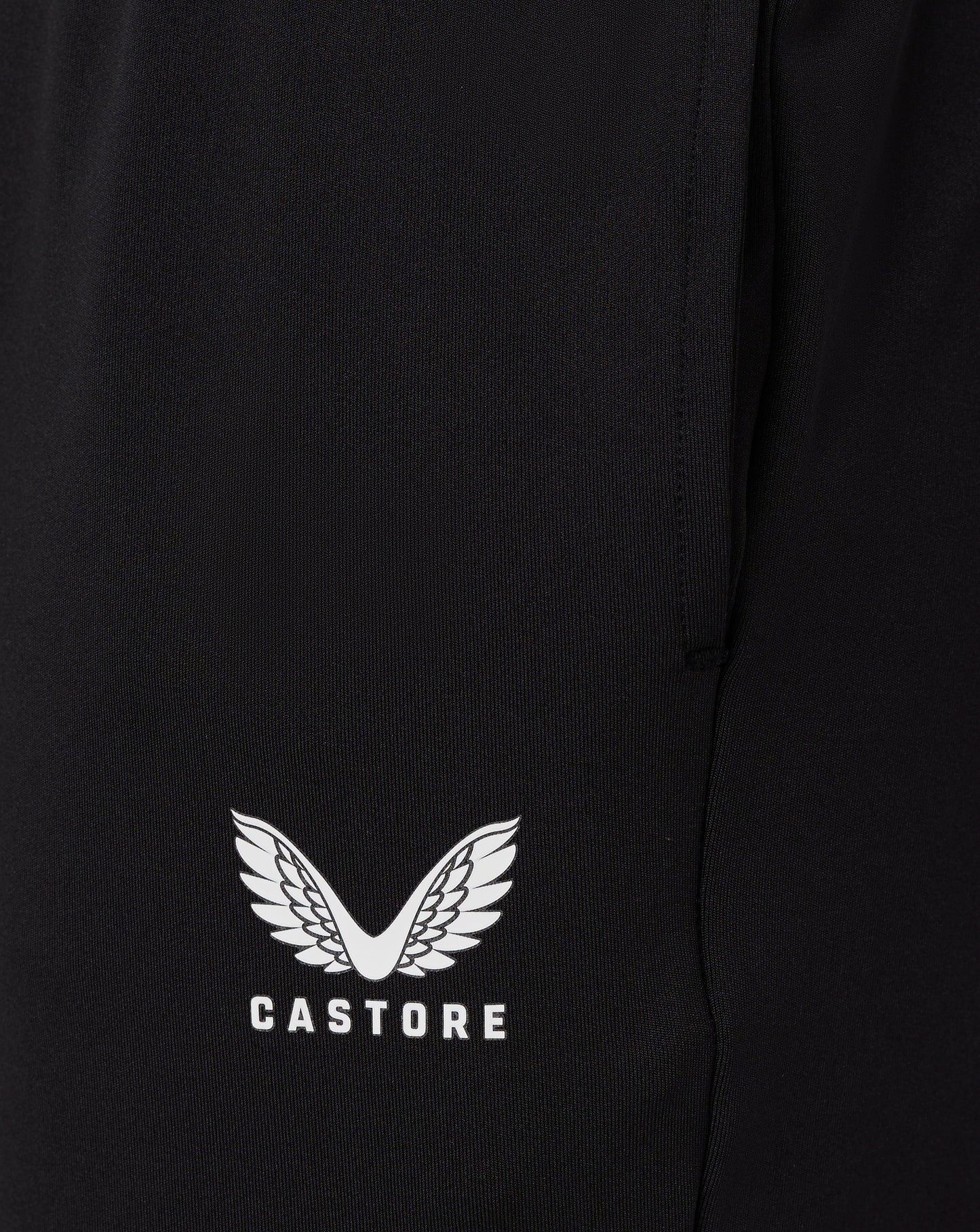 Close up of black fabric from Junior Slim Fit Pant with a white Castore wing logo at the hem