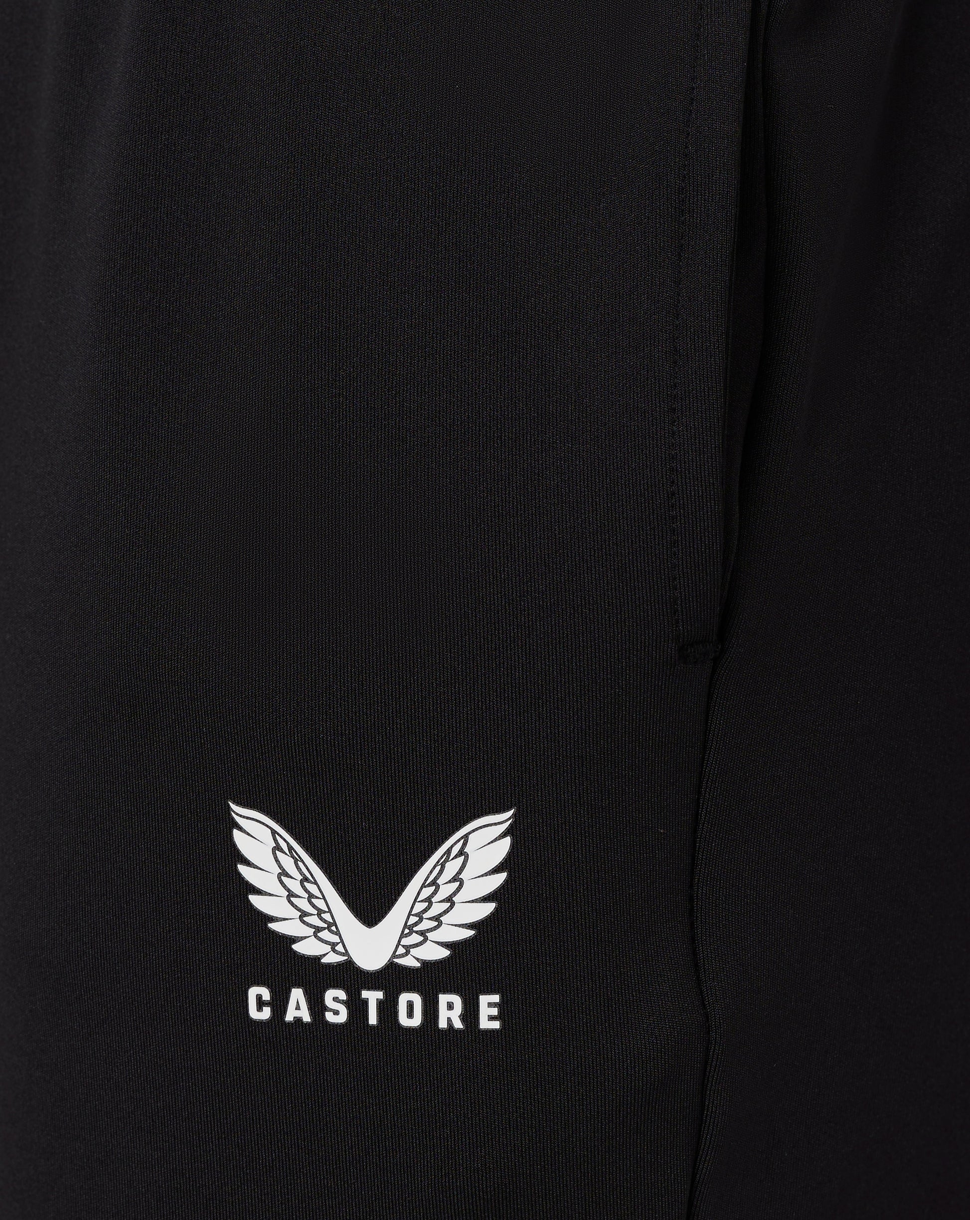 Close up of black fabric from Junior Slim Fit Pant with a white Castore wing logo at the hem