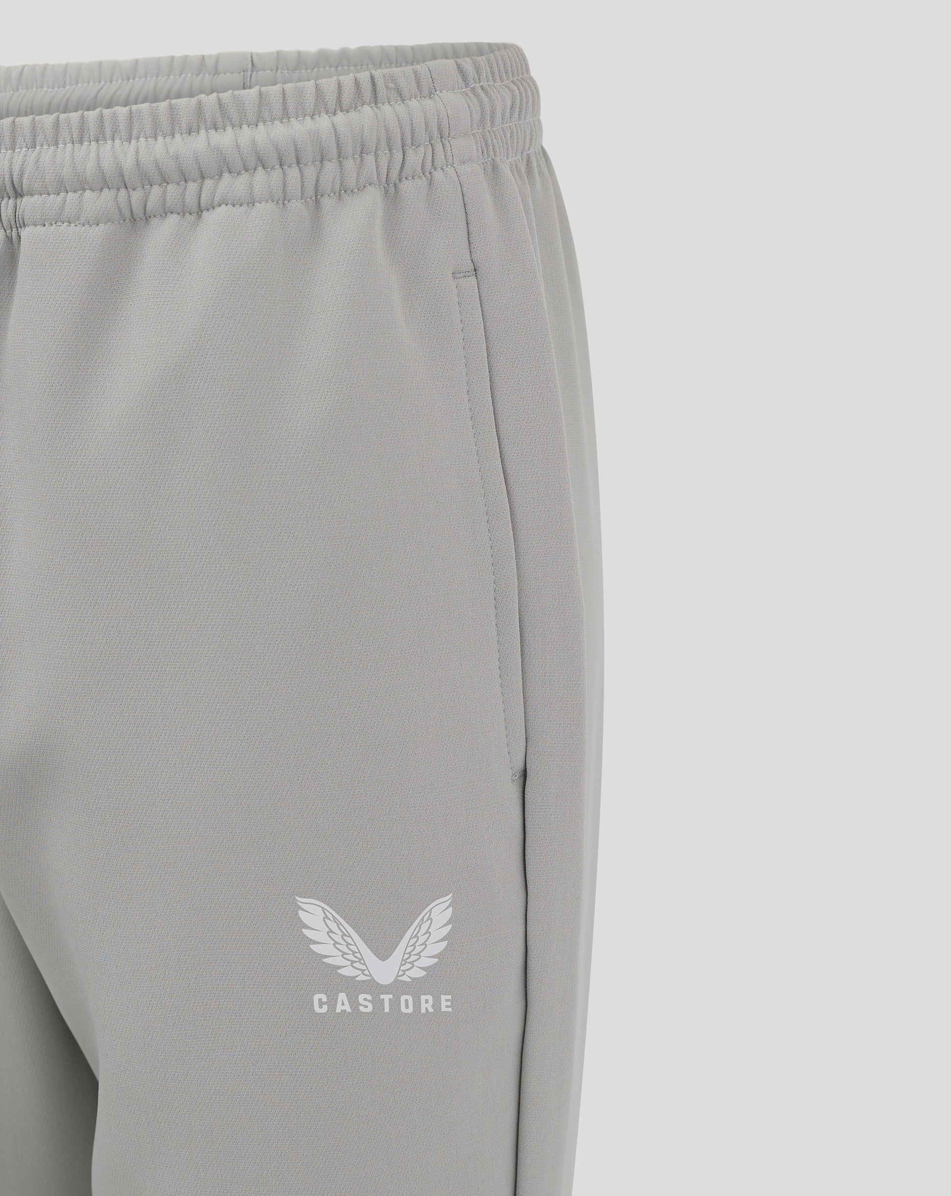 Close-up of grey track pants showing elastic waistband and Castore logo near the hem