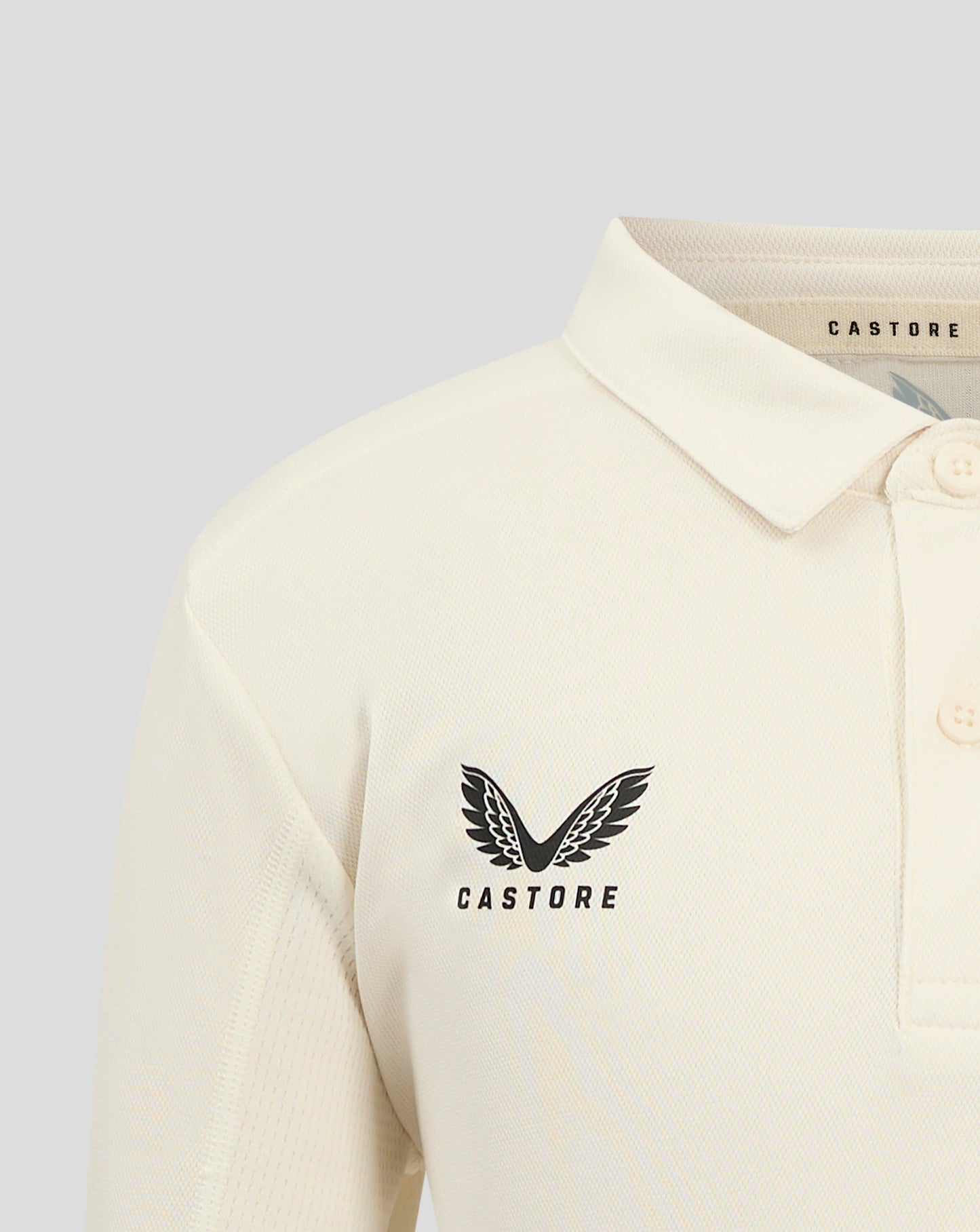 Close up of collar and neck area of Cannoli Cream junior cricket shirt showing beige neck tape and Castore branding