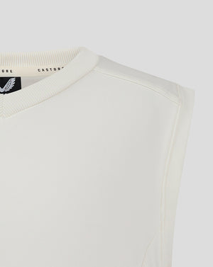 Close-up of the cream vest neckline showing ribbed V neck and Castore label inside.