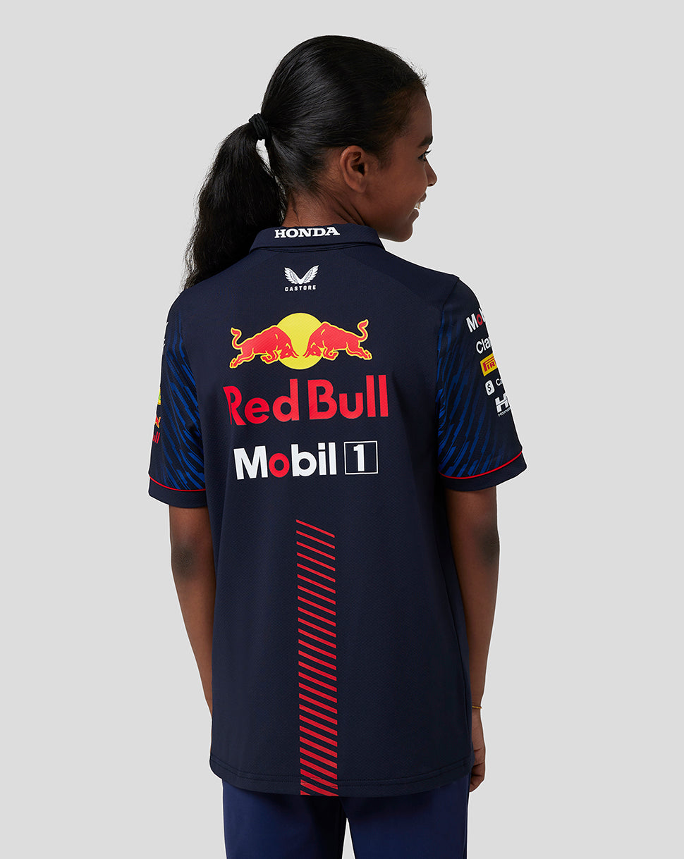 Back view of junior in navy Oracle Red Bull Racing polo showing large Red Bull logo on the back.