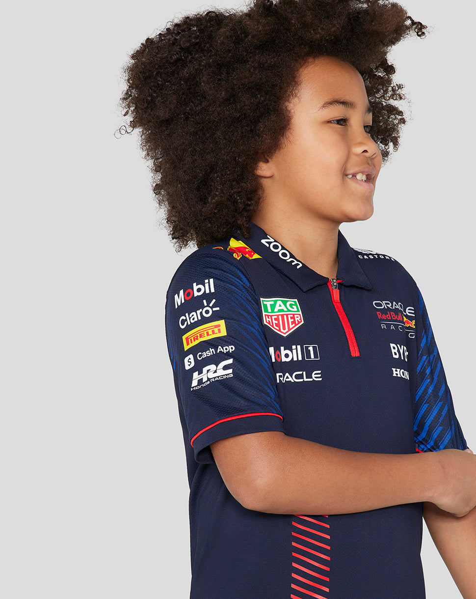 Side profile of a young child wearing a navy Night Sky polo with sponsor logos from Oracle Red Bull Racing