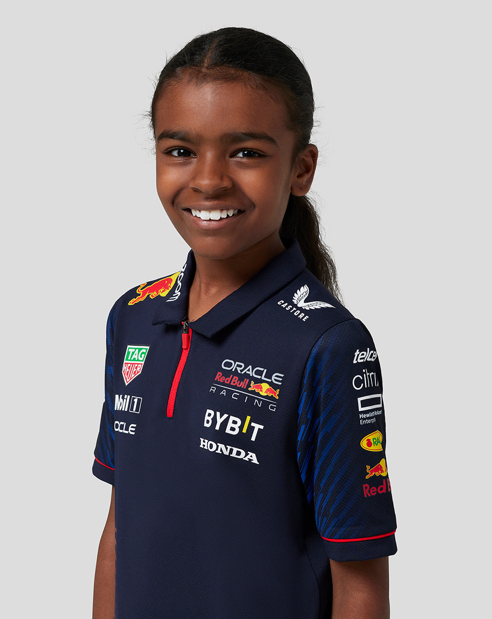 Close-up of a smiling girl in a navy Red Bull Racing polo showing sponsor logos on the chest.