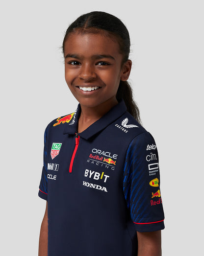 Close-up of a smiling girl in a navy Red Bull Racing polo showing sponsor logos on the chest.