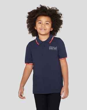 Child wearing navy Night Sky Oracle Red Bull Racing Junior Core Polo with red collar trim and logo on chest