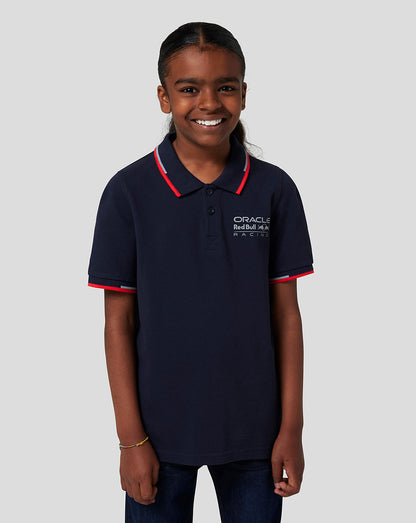Girl wearing Night Sky navy Oracle Red Bull Racing Junior Core Polo with red trim and logo on chest