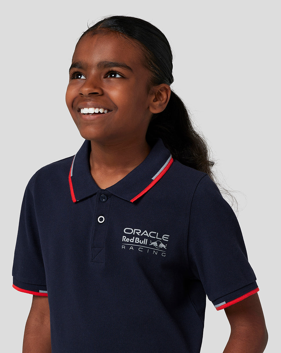 Young girl in navy Oracle Red Bull Racing polo with logo on chest and red trim