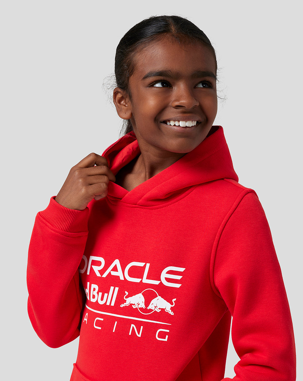 Smiling girl in Flame Scarlet Oracle Red Bull Racing Core Overhead Hoodie with a large logo on the front