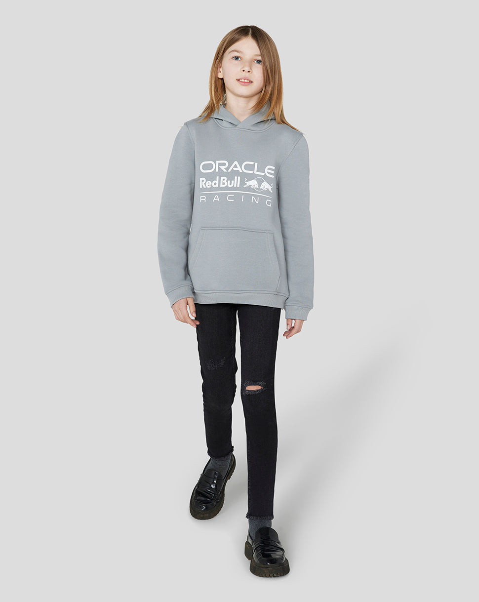 Girl wearing a light grey Oracle Red Bull Racing Junior Core Overhead Hoodie with a white logo across the chest